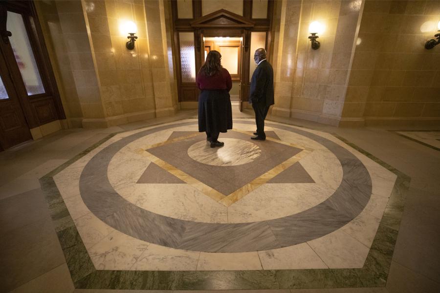 Two people talk in a government office.