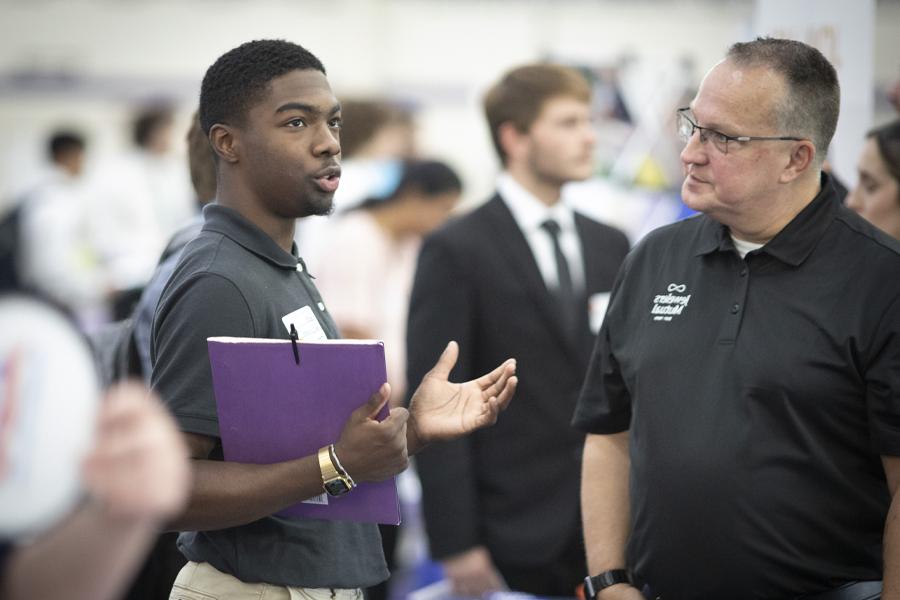 A business student speaks with a potential employer at a career fair.