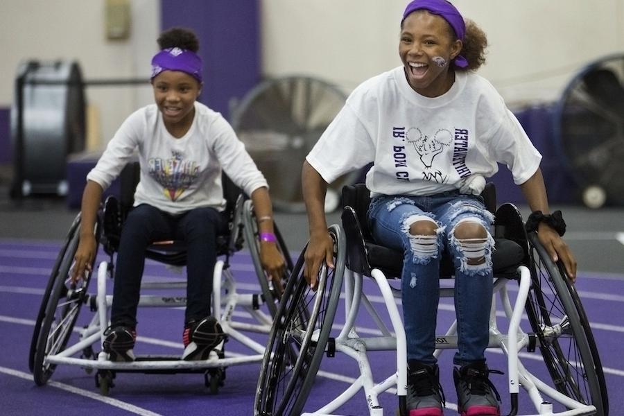 Image of two teenage girls playing wheelchair basket ball at Family Fest.